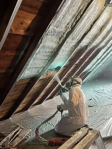 Spray foam being installed between roof rafters