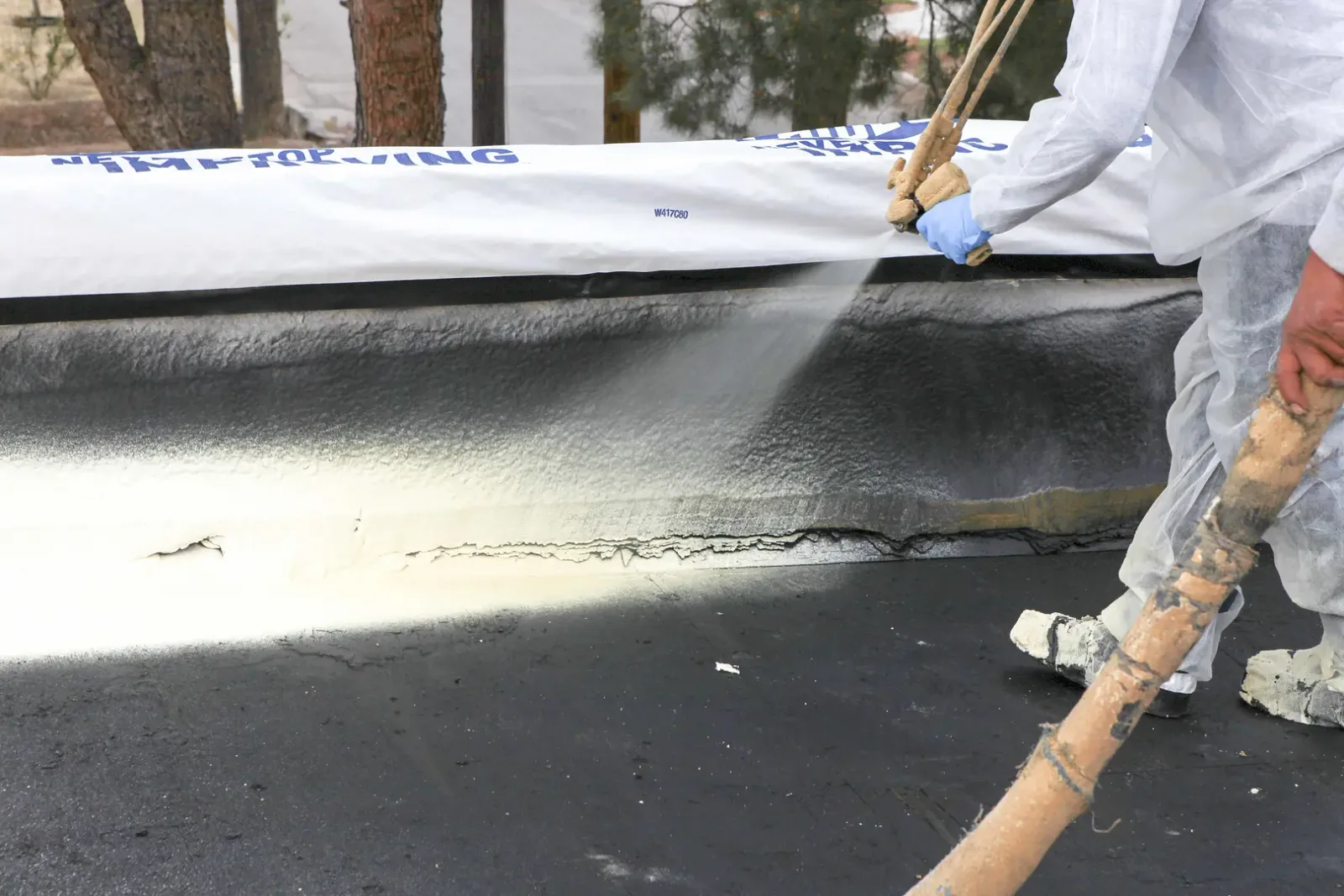 Spray foam applied to a roof by an installer in protective equipment
