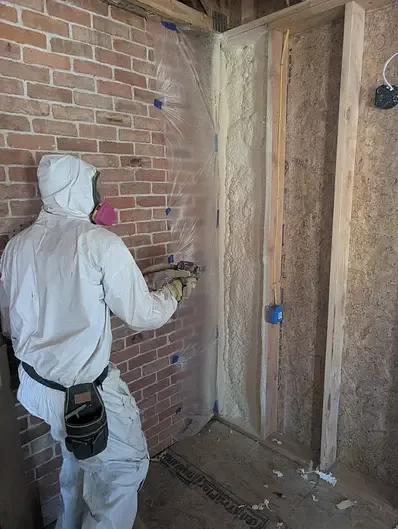 Installer applying spray foam to an interior wall