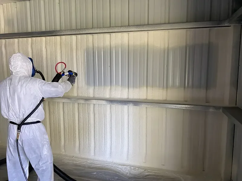 Installer applying spray foam inside a metal building